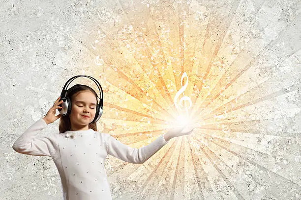 Little girl in headphones with eyes closed enjoying music