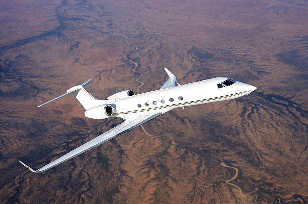 A corporate jet flying over a barren desert landscape in the Sudan. Overhead view in late afternoon light.