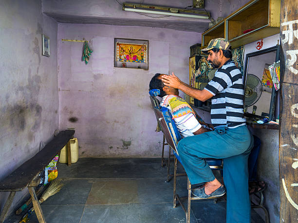 Jodhpur, India- March 6, 2015: Barber massaging a customers face after finishing a wet shave in a small barbershop of Jodhpur.