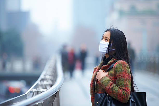 young woman wearing mask in the foggy city picture of one young asian woman wearing mask in the haze and foggy city. chengdu photos stock pictures, royalty-free photos & images
