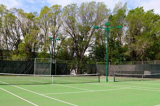 istock Tennis courts with green lights and bright green trees 476506092