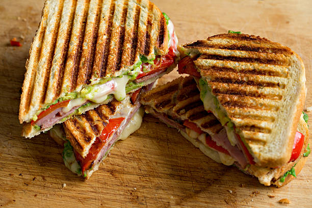Ham And Cheese Panini A high angle extreme close up shot of  two sliced ham and cheese grilled sandwiches, also known as  paninis. panino stock pictures, royalty-free photos & images