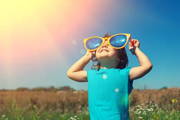 Photo of Little girl with big sunglasses enjoys sun