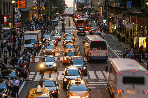 Commuters crossing busy 42nd Street in New York City, USA in afternoon. Vast number of people and vehicles hit the streets and avenues of Manhattan every day.
