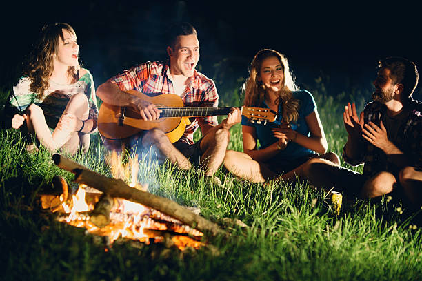 istock Friends playing guitar gathered around campfire. 476540962