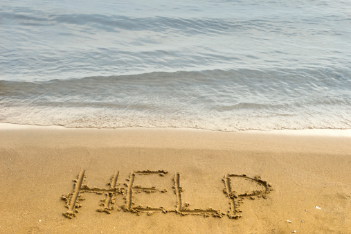 The word help is carved in the sand in the conceptual photo