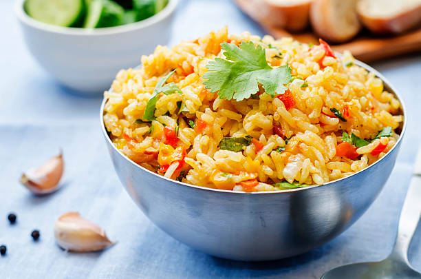 saffron rice with vegetables and cilantro saffron rice with vegetables and cilantro on a blue background. the toning. selective focus spanish culture stock pictures, royalty-free photos & images