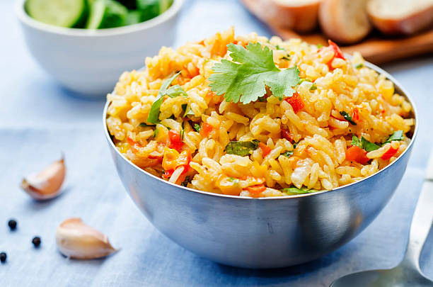 saffron rice with vegetables and cilantro saffron rice with vegetables and cilantro on a blue background. the toning. selective focus pilau rice stock pictures, royalty-free photos & images