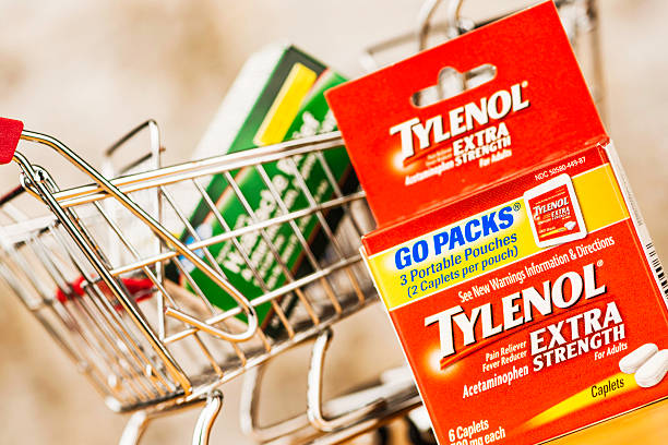 Generic brand pain medication vs name brand Tylenol. Pain relief. Peyton, Colorado, USA - June 7, 2015: A horizontal studio shot of the name brand pain relief medication, Tylenol in front of a box of generic pain relief tablets that contain similar ingredients. The generic brand is in a shopping cart to portray the concept of choosing the less expensive generic option for pain medication. bayer schering pharma ag photos stock pictures, royalty-free photos & images