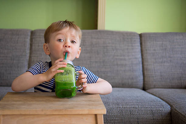 милый ребенок питьевой зеленый коктейль - vegetable smoothie drink multiple exposure стоковые фото и изображения