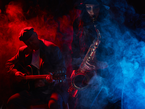 Saxophonist, beautiful young woman, smoky stage and guitarist on background