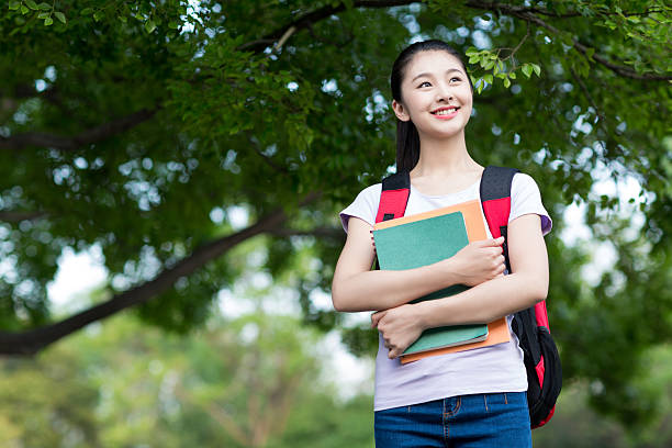 istock female student outdoors holding a notebook and smiling 476552342