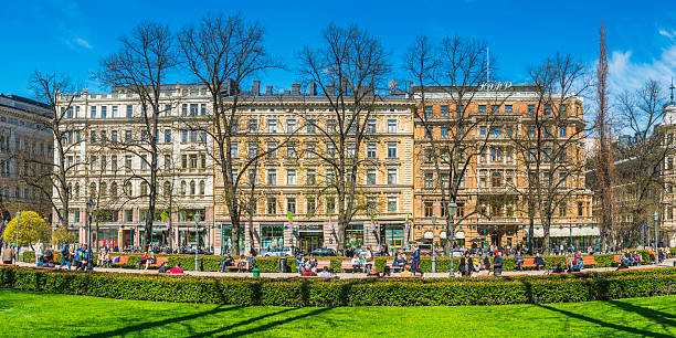 Crowds of shoppers, tourists and locals enjoying the spring sunshine in the green oasis of Esplanadi park overlooked by the boutiques and department stores of central Helsinki, Finland's vibrant capital city. ProPhoto RGB profile for maximum color fidelity and gamut.