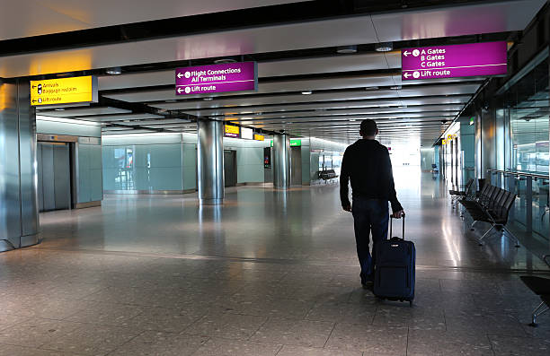 Man with suitcase at an airport lobby. Man with suitcase at an airport lobby. heathrow airport stock pictures, royalty-free photos & images