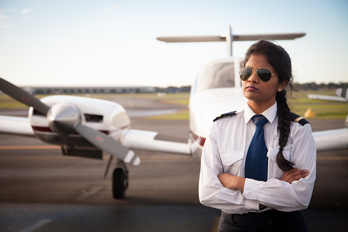 A female pilot stands in front of her aircraft