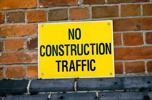 A bright yellow sign on a wall, which reads “No Construction Traffic”.