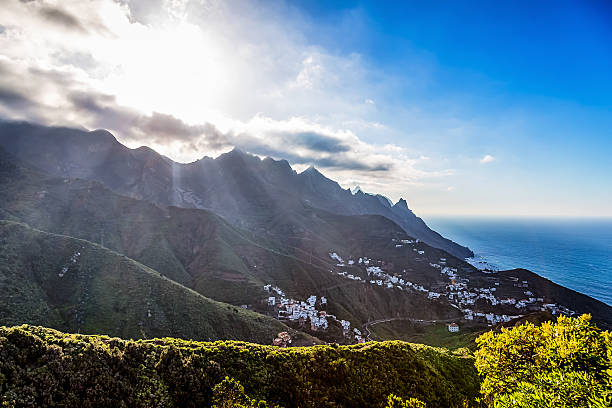 istock Mountains with clouds and sun over small village 476562664
