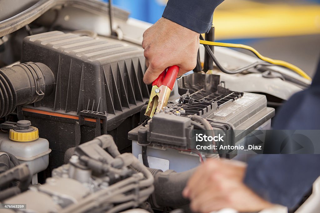 Jump starting a car Closeup of the hands of a mechanic using jumper cables to start a car Jump Start Stock Photo