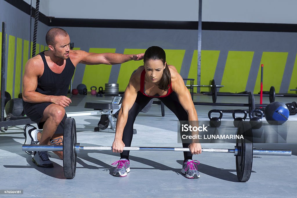 Hombre de gimnasio con entrenador personal de mujer levantamiento de peso bar - Foto de stock de 20 a 29 años libre de derechos
