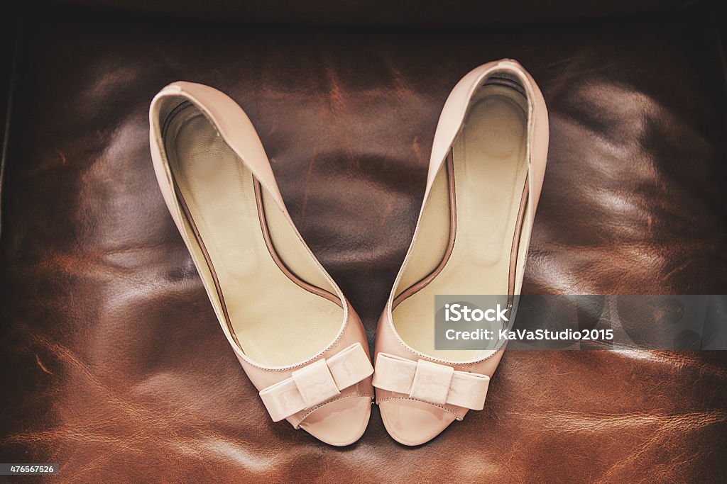 Beautiful shoes on the couch Wedding shoes beige stand on a leather sofa brown 2015 Stock Photo