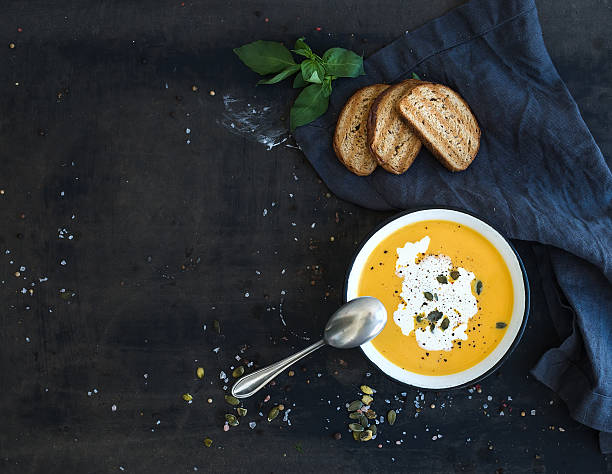 Pumpkin soup with cream, seeds, bread and fresh basil on