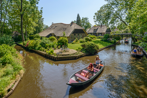 Giethoorn, The Netherlands - June 5, 2015: Tourists in boats on the canal of the famous village of Giethoorn in Overijssel, The Netherlands on a sunny summer day.