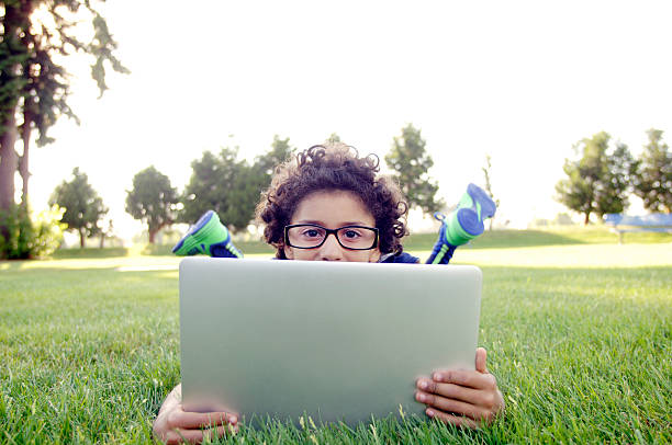 African American boy working on a laptop computer outside. stock photo