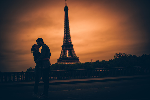 Photo of loving couple enjoying together in the city of love, Paris. They are kissing and behind them is Eiffel Tower.