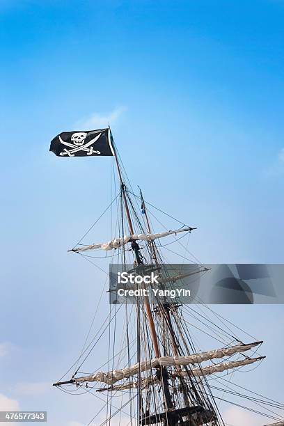 Foto de Jolly Roger Caveira E Ossos Cruzados Bandeira Com Mastro De Um Navio Pirata e mais fotos de stock de Cor Preta