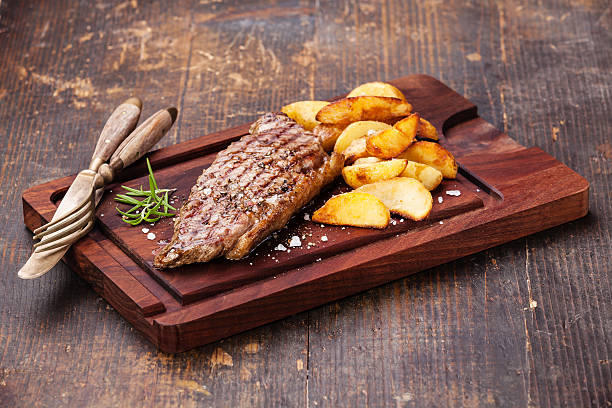 bistecca di manzo con patate arrosto con zeppa - steak strip steak prepared potato grilled foto e immagini stock