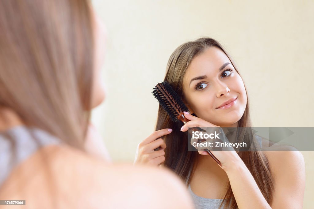 Girl at mirror combing her hair Almost ready. Close-up of girl at mirror combing her hair at home. 2015 Stock Photo