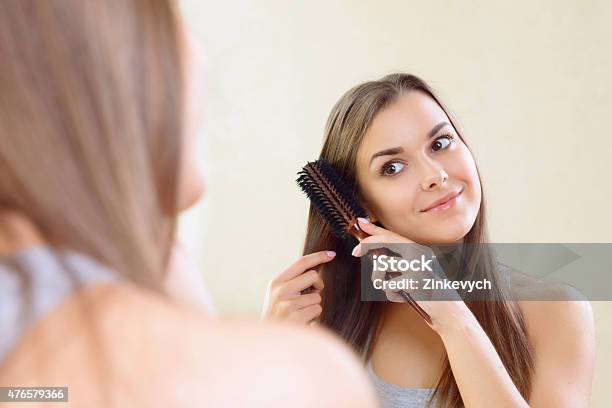 Girl At Mirror Combing Her Hair Stock Photo - Download Image Now - 2015, Adult, Applying