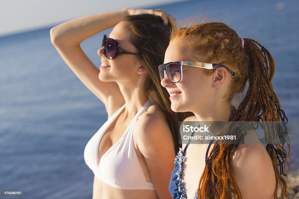 Due ragazze adolescenti in occhiali da sole, prendere il sole sulla spiaggia - Foto stock royalty-free di Abbronzarsi