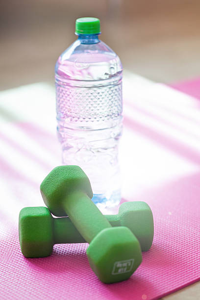 istock Two dumbbells with mineral water on yoga mat 476581334