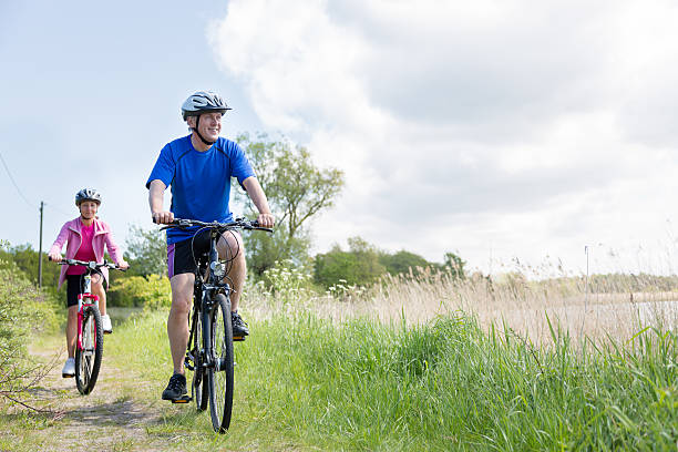 coppia matura all'aperto in bicicletta nella natura - mature adult bicycle senior adult heterosexual couple foto e immagini stock