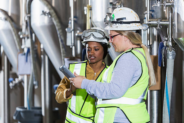 istock Women with hardhats in factory looking at digital tablet 476586202