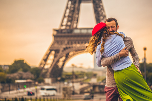 Photo of young loving couple sharing their love and affection in front of the Eiffel tower in Paris, France.