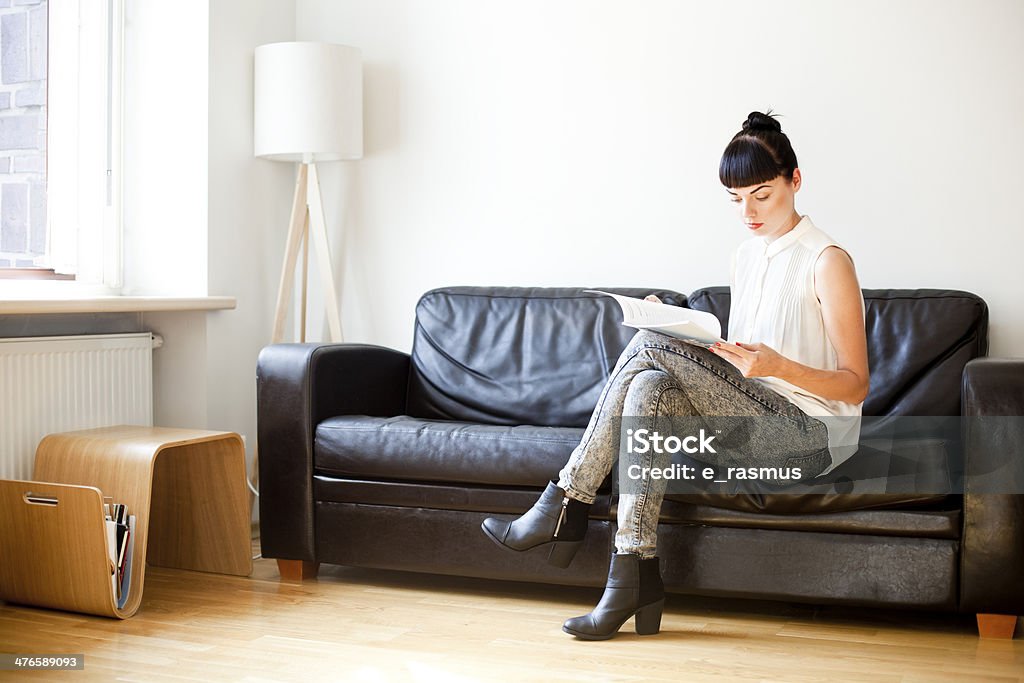 Woman Reading Young businesswoman working from home, reading an article. Magazine - Publication Stock Photo