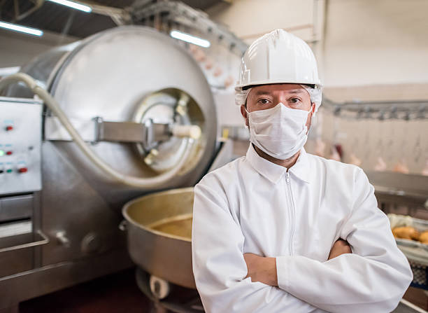 Man working at a food factory Man working at a food factory posing in front of a machine meat factory stock pictures, royalty-free photos & images