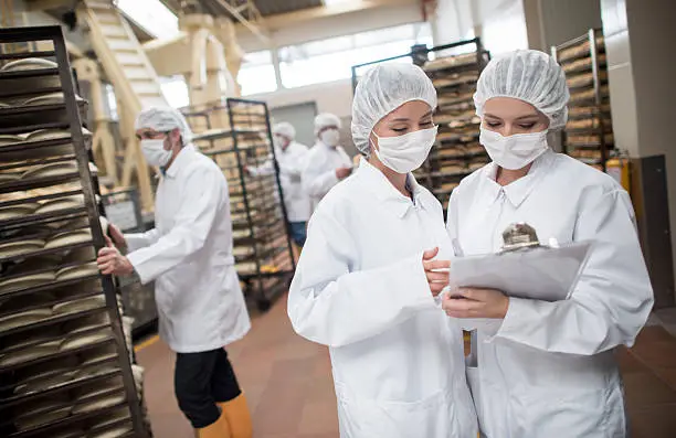 Women working at a food factory and looking at checklist on a clipboard