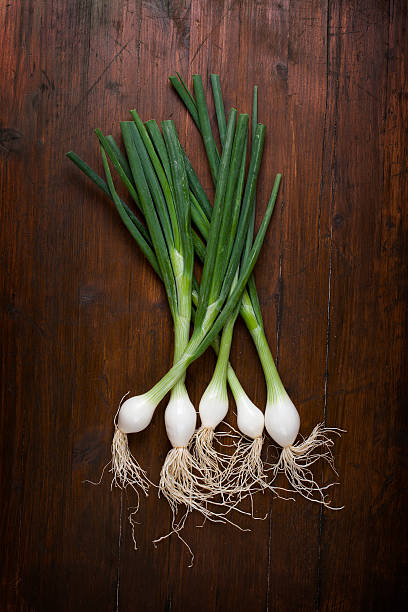 bunch of spring onions on wood stock photo