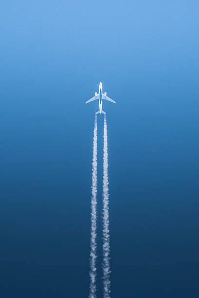 White airplane in flight against blue background stock photo