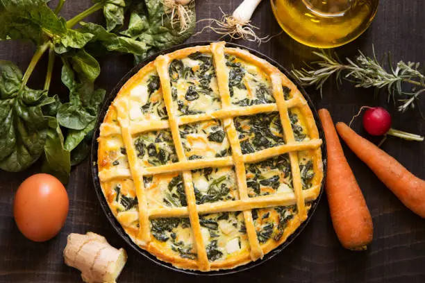 Vegetarian pie with ingredients on a black wooden background