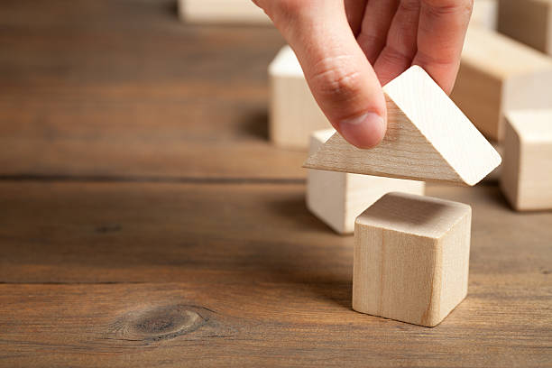 istock Wooden toy house with hand on old table 476605742