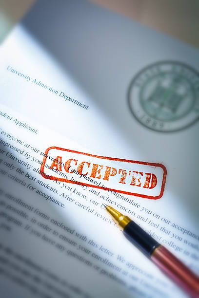 University Application Acceptance Notification Letter with ACCEPTED Stamp An acceptance letter from a university application. An university application form together with the letter of acceptance with a red rubber stamp of "Accepted" on a table top still life. Photographed close-up in vertical format with selected focus on the rubber stamp impression. college acceptance letter stock pictures, royalty-free photos & images