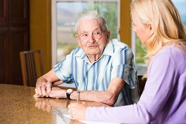 Photo of Smiling senior man talking to social worker at the counter