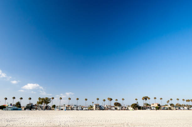 A row of beach front homes along the sand at Belmont Shore, in Long Beach, CA. A strip of white sand can be seen at the bottom, with clear deep blue sky taking up much of the space. This area is perfect for copy. The photo was taken with a polarizer filter to accentuate the deep blue sky.