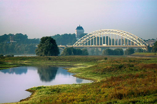 Bridge over the river Waal in Nijmegen, The Netherlands. Water in the foteground and the reconstruction of a castle tower in the background. The bridge is well known for its role in World war II and the battle of Arnheim.