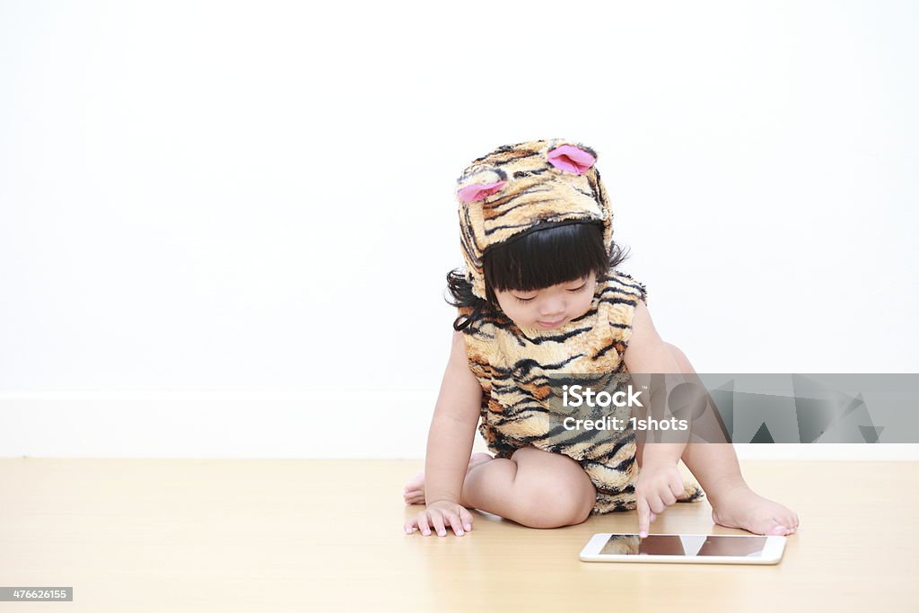 Asiatique petite fille en Costume de tigre avec tablette électronique - Photo de 12-17 mois libre de droits