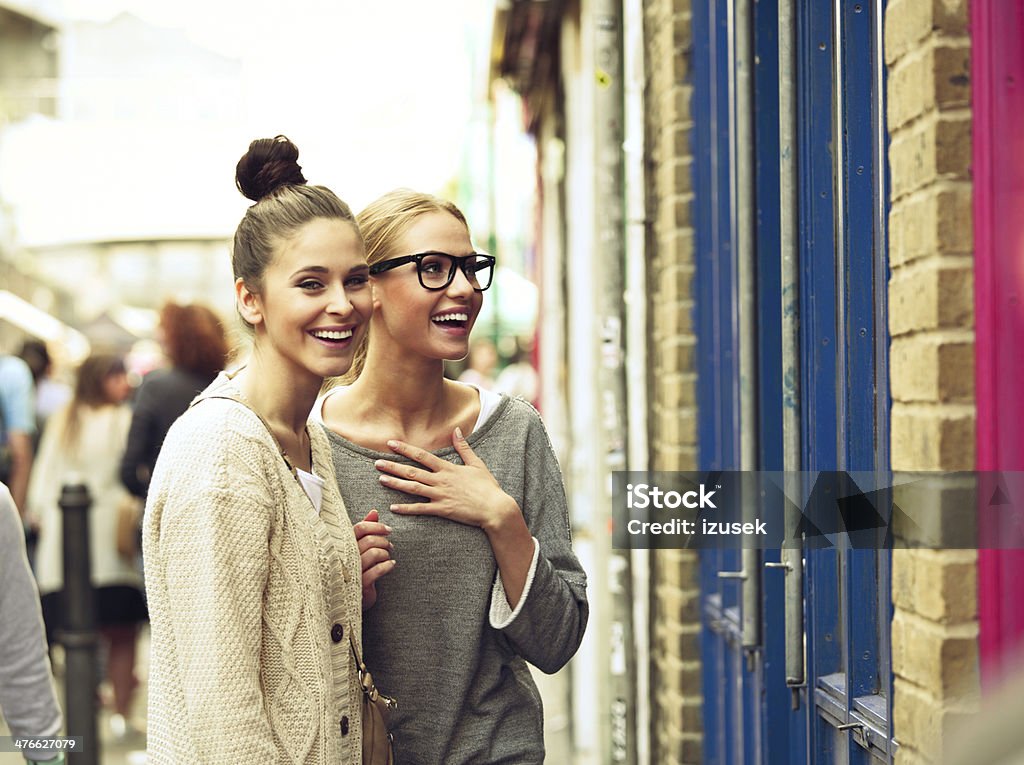 Girls in the city Female friends standing at a shopwindow, having fun. Street Stock Photo